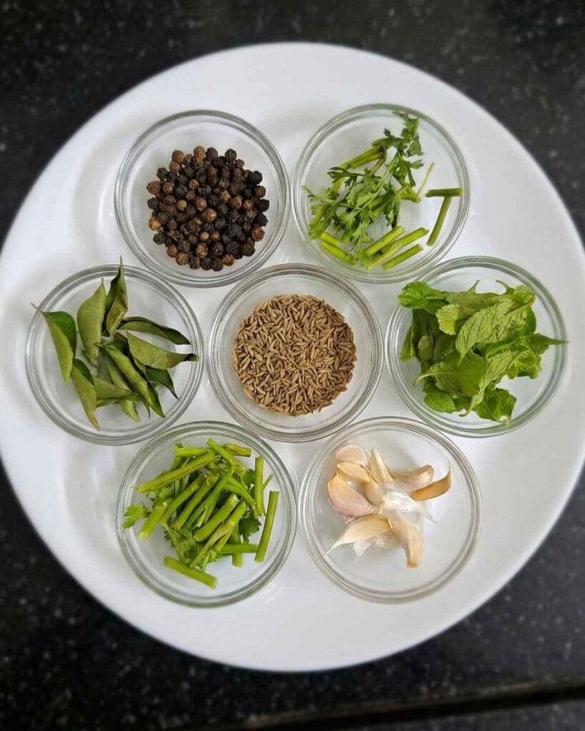 Ingredients for mint rasam including mint leaves, pepper, cumin seeds, garlic, curry leaves, and coriander stems.