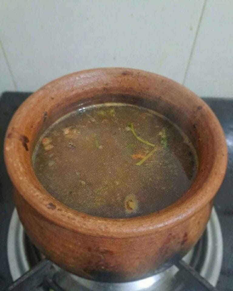 Mint rasam without tempering simmering in a clay pot, made with tomato, mint, pepper, and cumin.