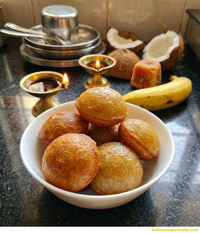 Nei Appam placed in a white bowl with coconut jaggery banana and oil lamps in the background, perfectly golden and fluffy South Indian ghee appam.