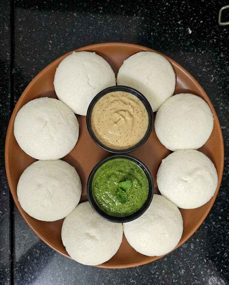 Idli recipe (இட்லி) served with chutney showing soft and fluffy South Indian idlis