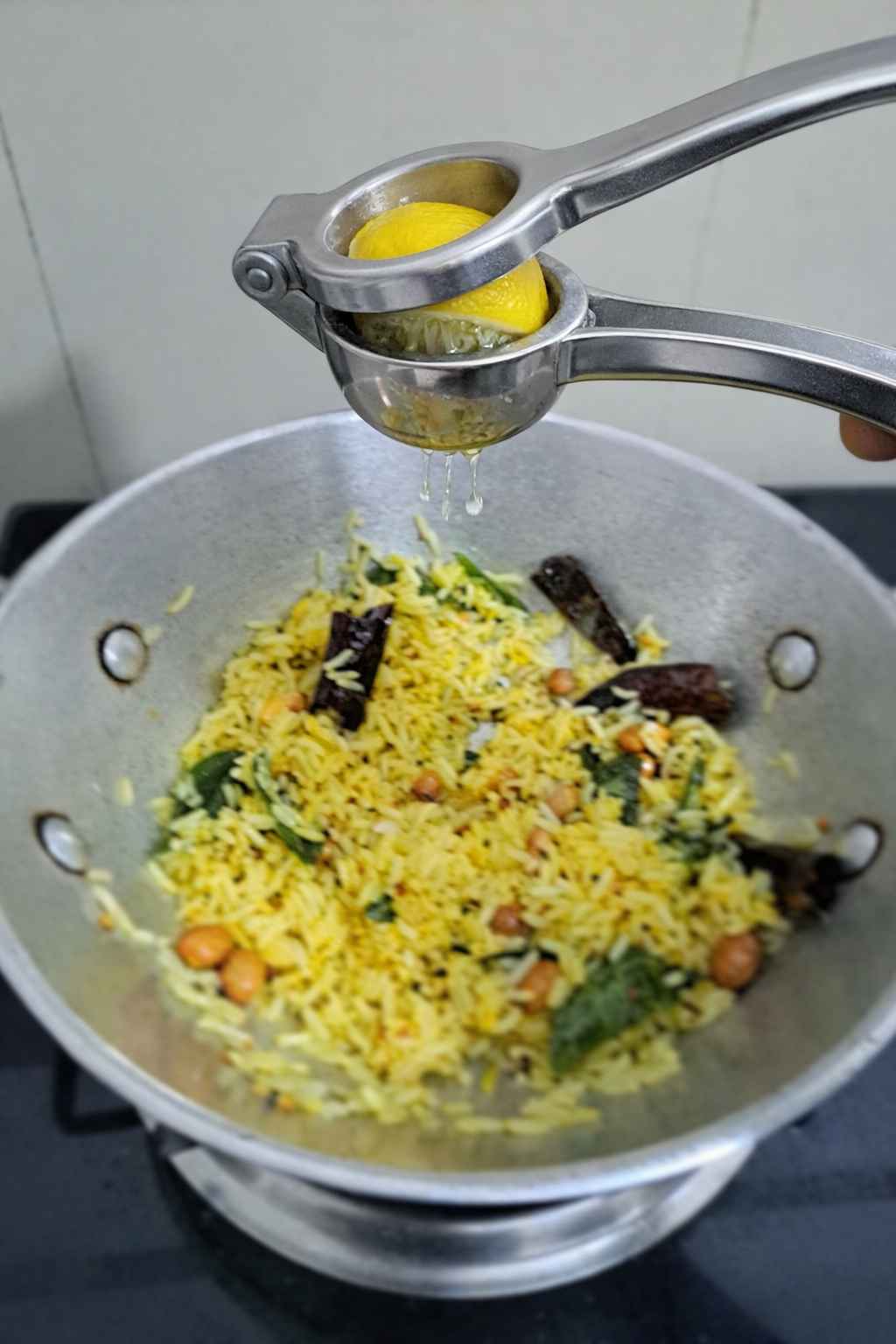 A close-up shot of vibrant yellow lemon rice garnished with crunchy roasted peanuts and fresh curry leaves.