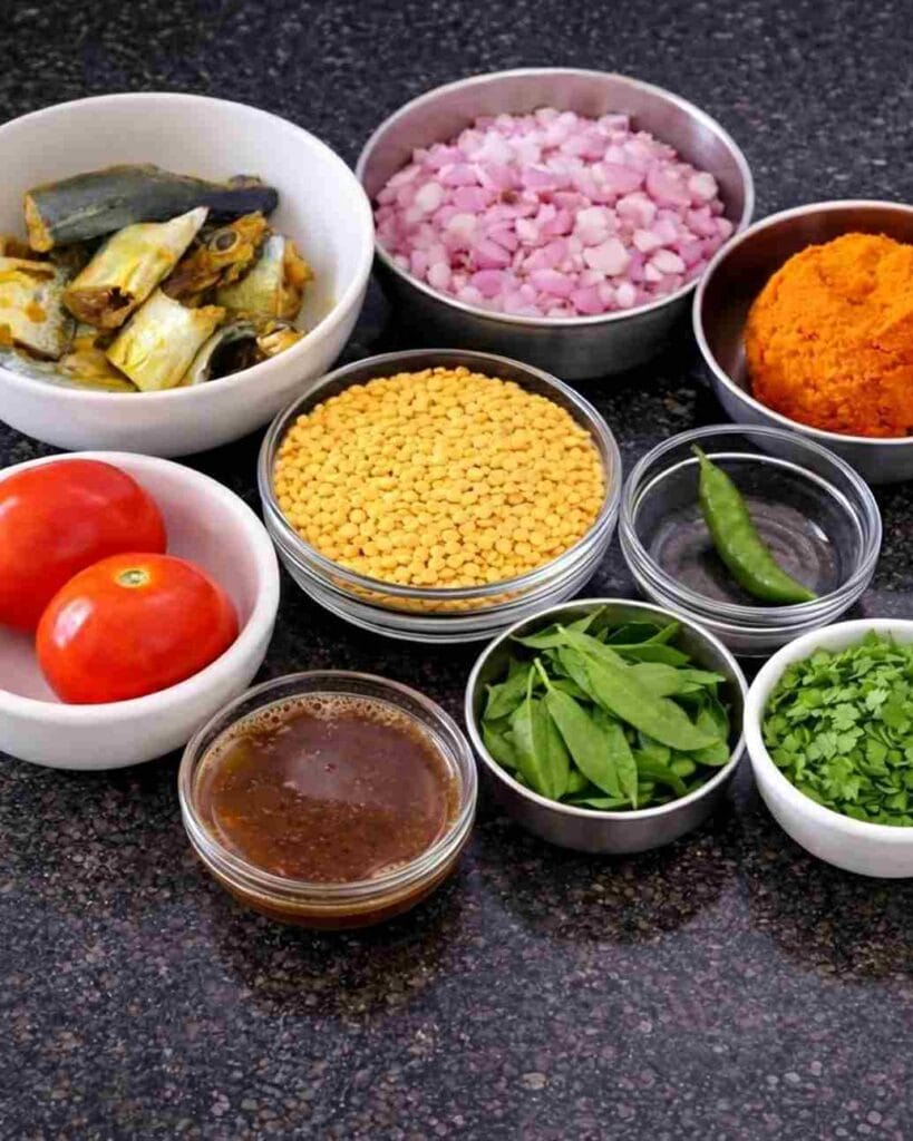 Ayila meen kulambu ingredients including fish head pieces, onions, tomatoes, tamarind, curry leaves, and homemade masala