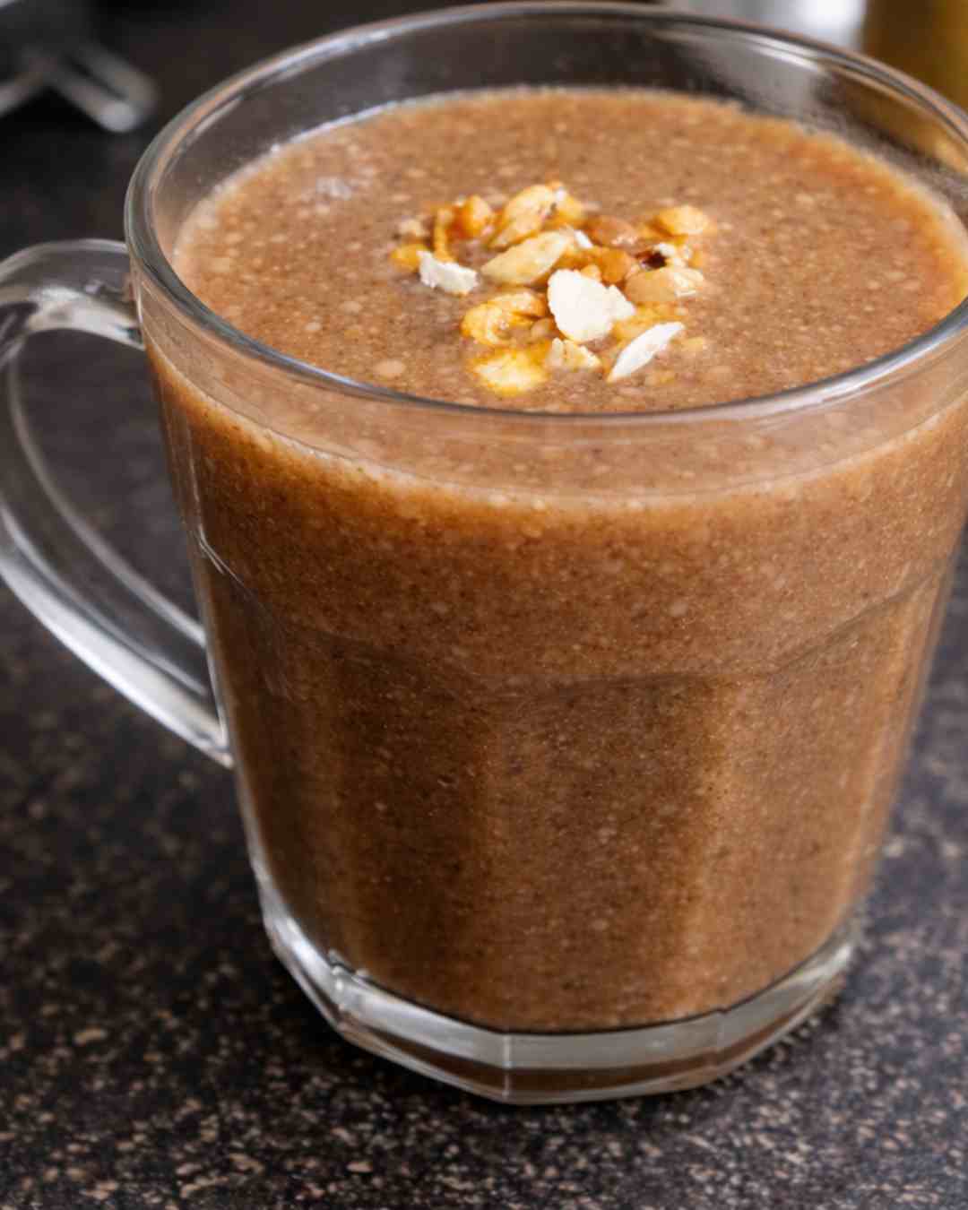 Karuppu ulundhu kanji served warm in a glass mug topped with roasted nuts for a high protein breakfast