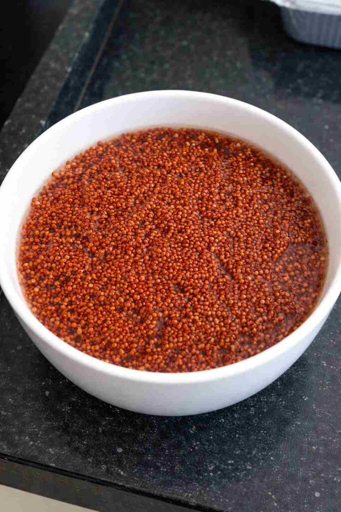 Cleaned whole ragi grains soaked in water before drying and grinding into ragi powder at home