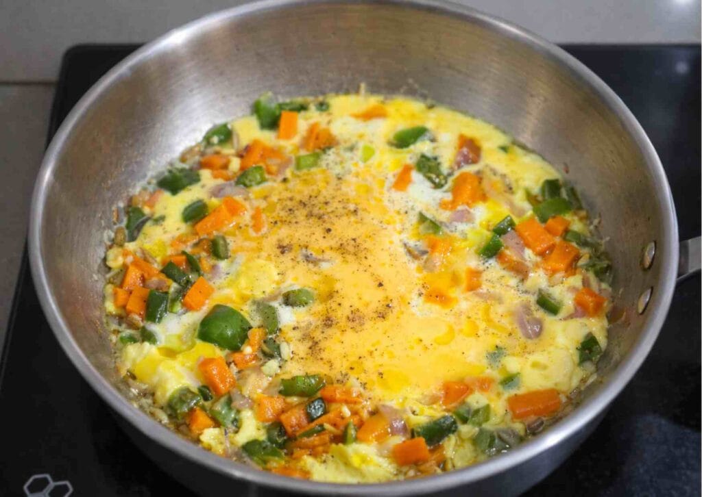 Beaten eggs poured over sautéed vegetables for quick egg fried rice recipe