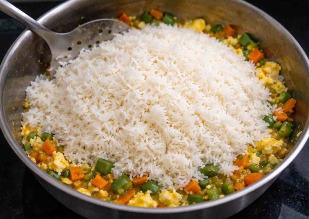 Cooked leftover white rice added to pan for quick egg fried rice recipe
