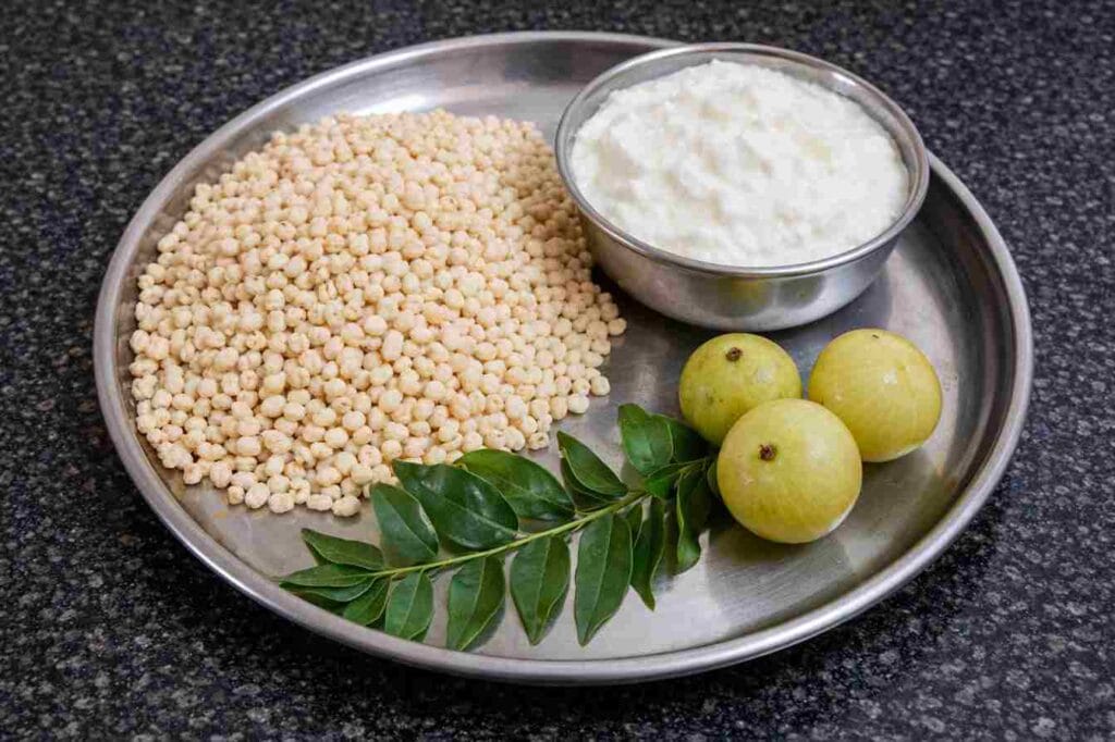 Ingredients for cholam kanji recipe including jowar, curd, amla and curry leaves for fermented jowar mor drink