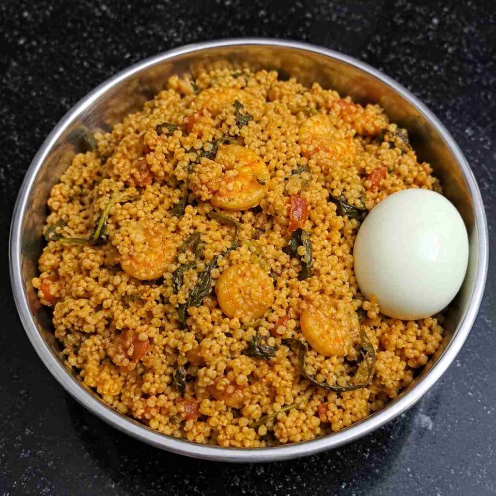 Fluffy kodo millet prawn biryani served hot with boiled egg in a steel bowl