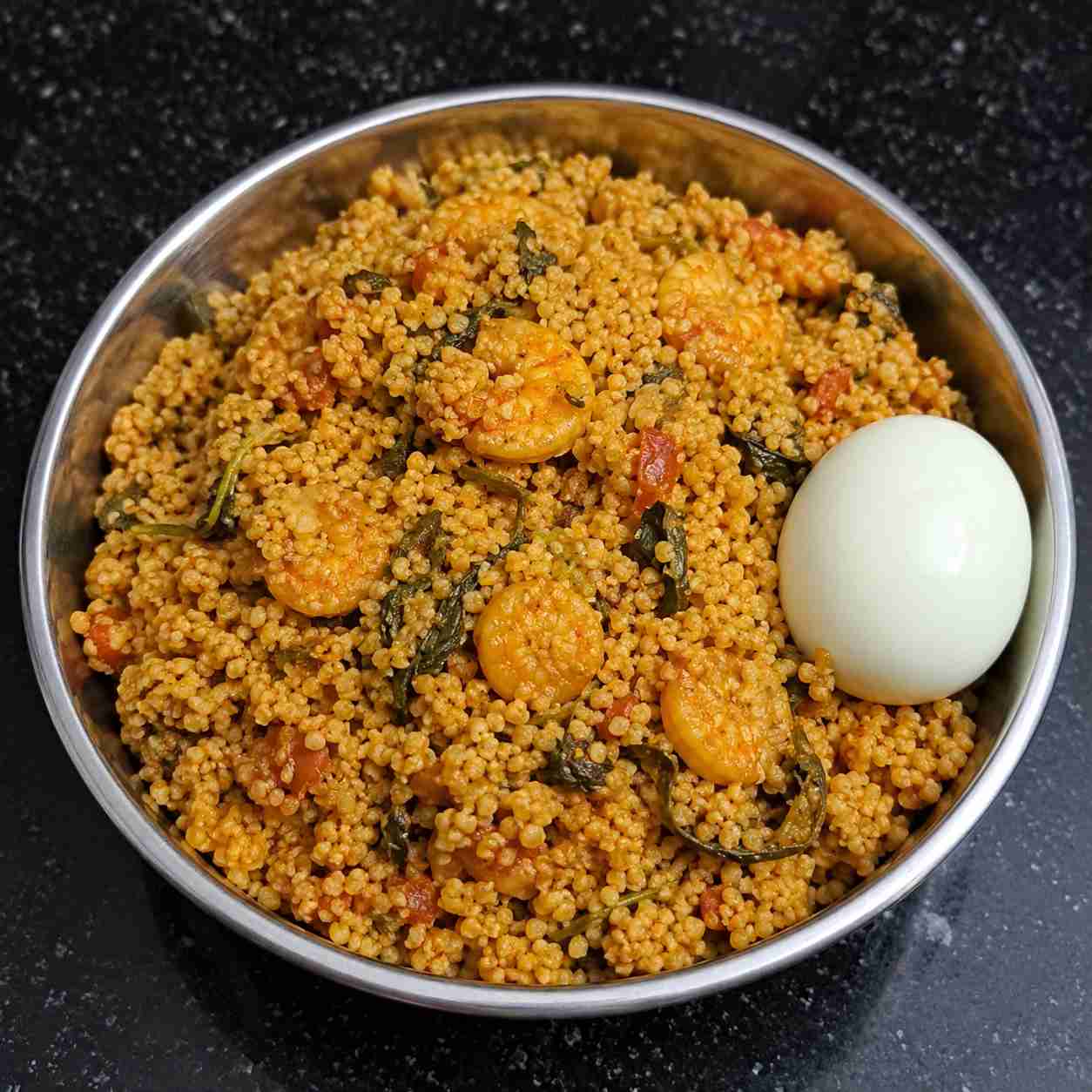 Fluffy kodo millet prawn biryani served hot with boiled egg in a steel bowl