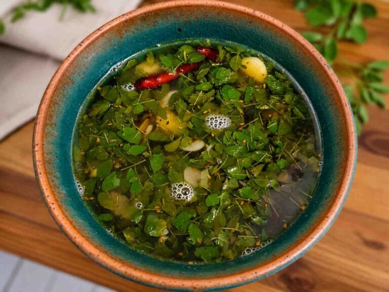Murungai keerai soup served hot in a bowl with moringa leaves, garlic, and pepper