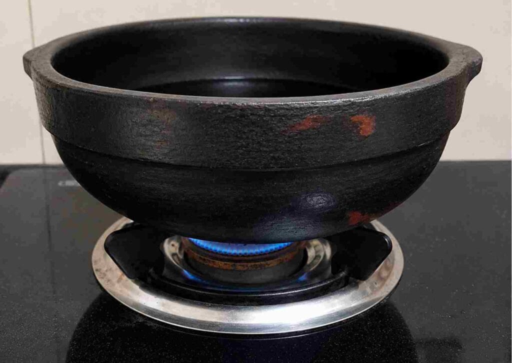 clay pot heating on stove with oil layer to enhance surface strength and prepare earthen cookware for cooking use