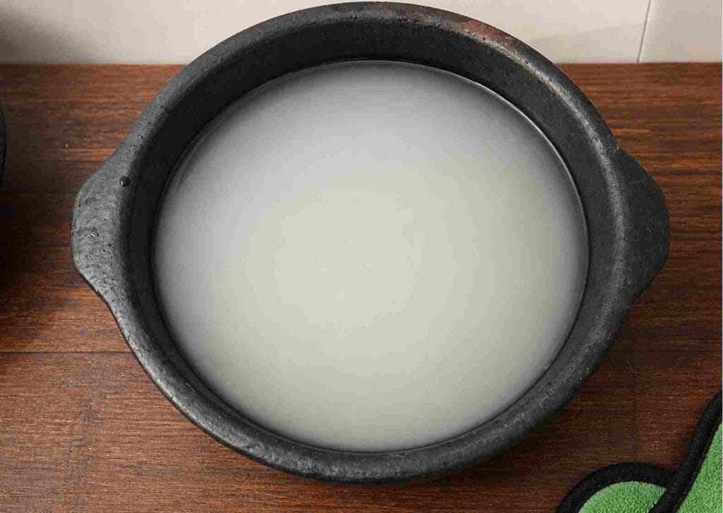 clay pot filled with rice starch water for natural seasoning process to strengthen earthen cookware before cooking use