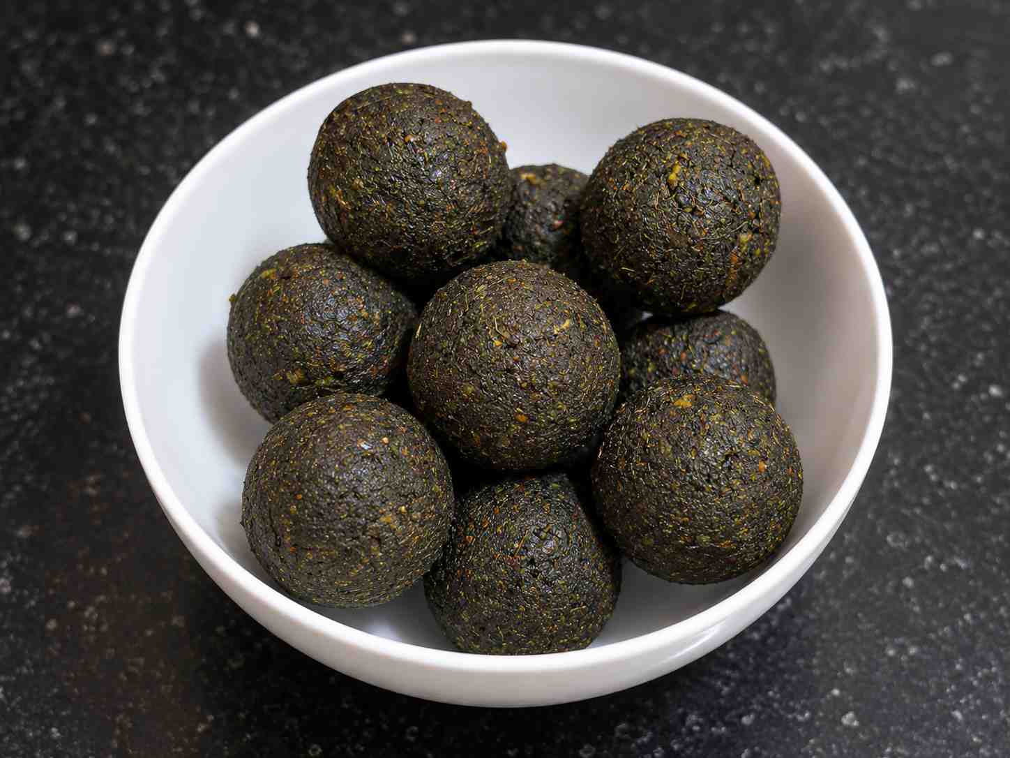 Healthy Curry Leaves Laddu made with dates almonds coconut and fresh curry leaves served in a white bowl