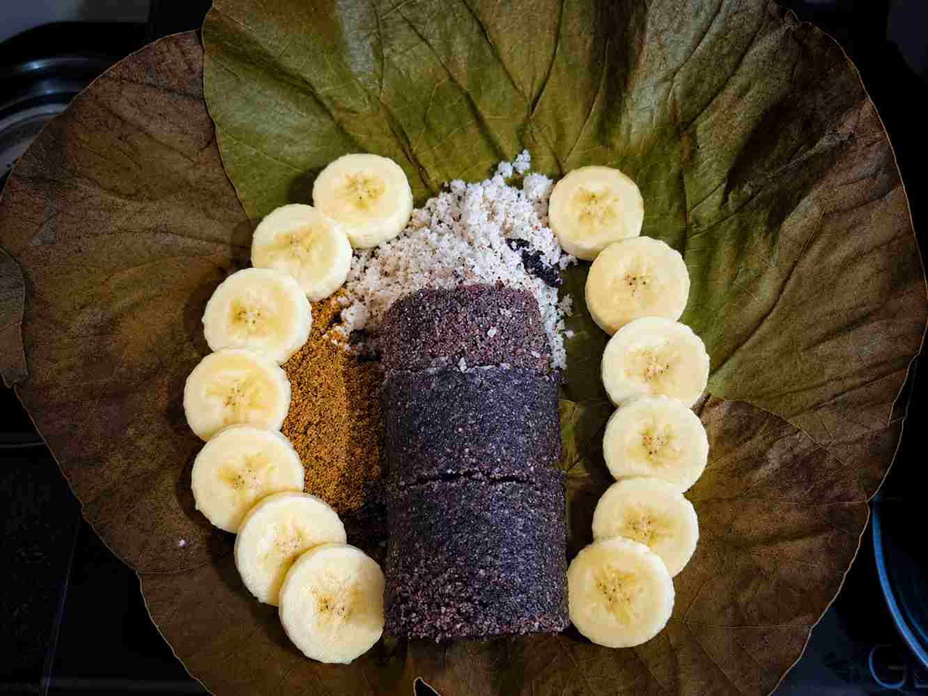 Traditional Kavuni Puttu Recipe made with black rice, coconut, jaggery, and banana served on a lotus leaf.