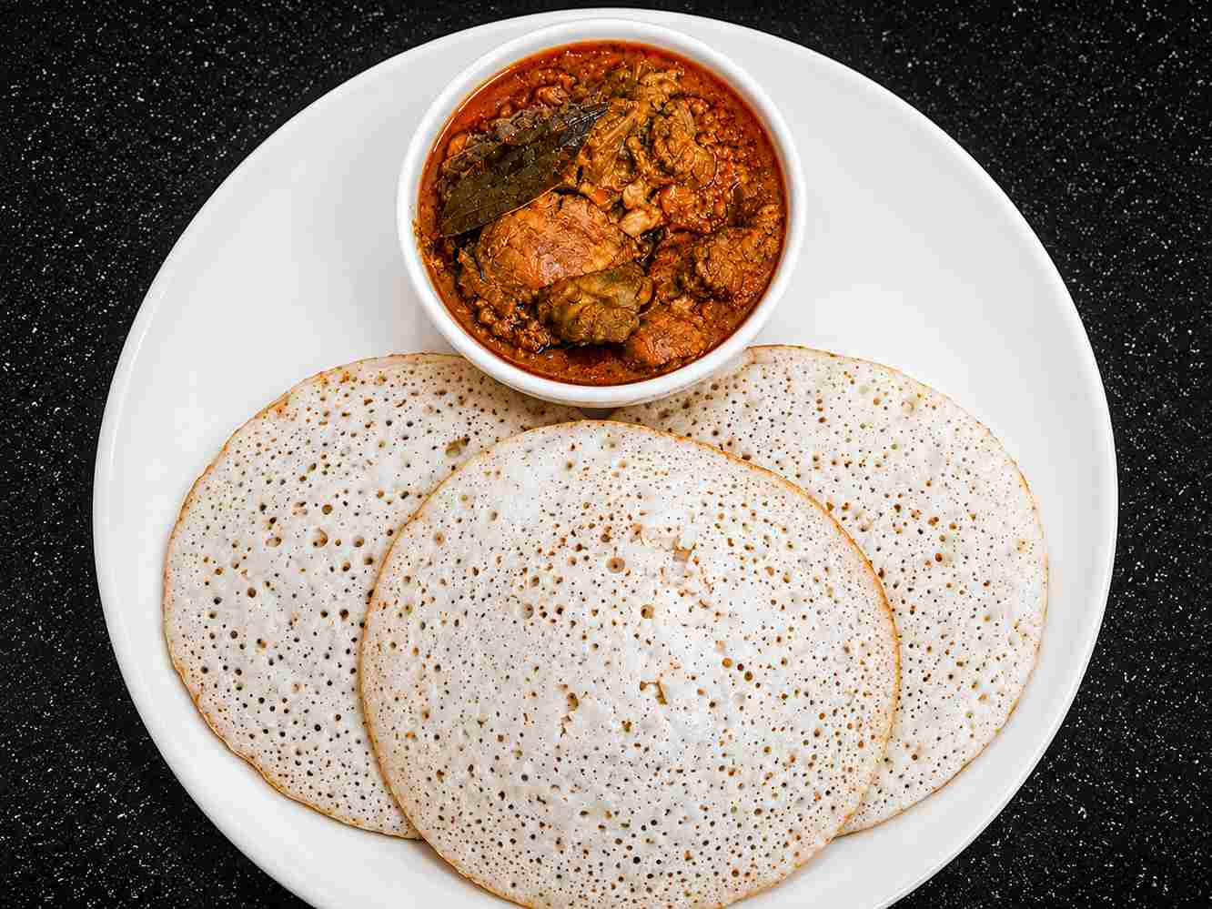 Soft coconut dosa recipe served with spicy gravy showing fluffy and spongy texture.