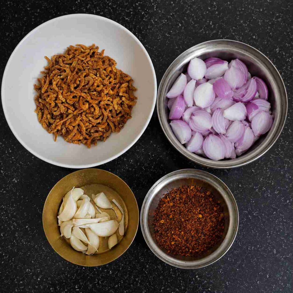 Dry prawns, sliced onions, garlic cloves, and homemade chilli flakes arranged for making traditional Eral Sambal.