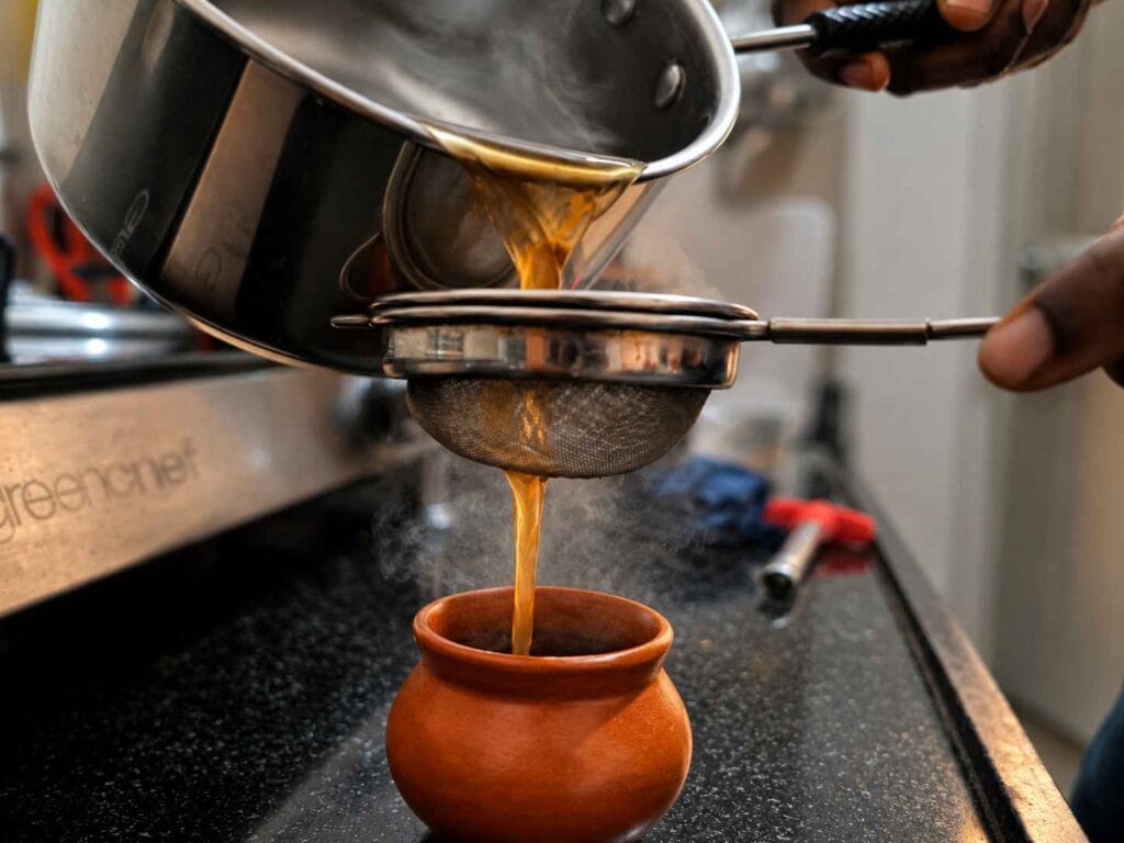 Hot Sukku Malli Coffee being filtered into a traditional clay cup