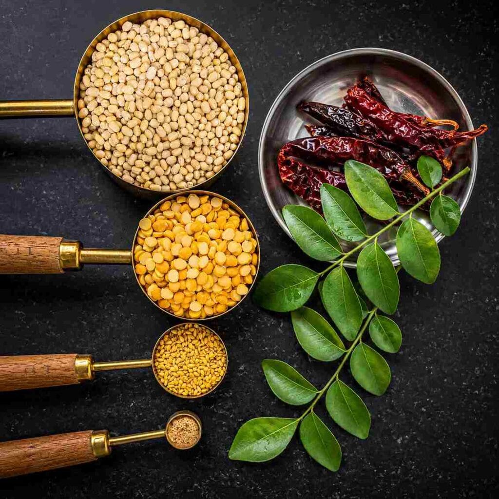 Ingredients for idli podi including urad dal, chana dal, sesame seeds, red chillies and curry leaves