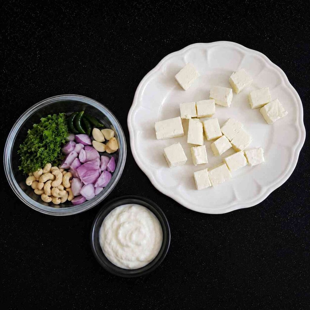 Ingredients for Simple Paneer Gravy Recipe including paneer, curd, onions, cashews, coriander, and green chillies