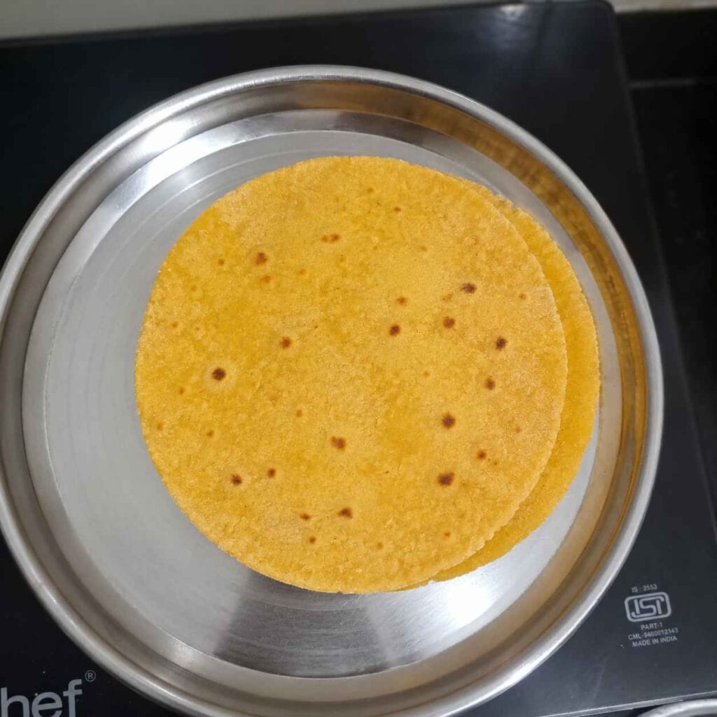 Soft homemade makki atta roti served on a steel plate after cooking on tawa
