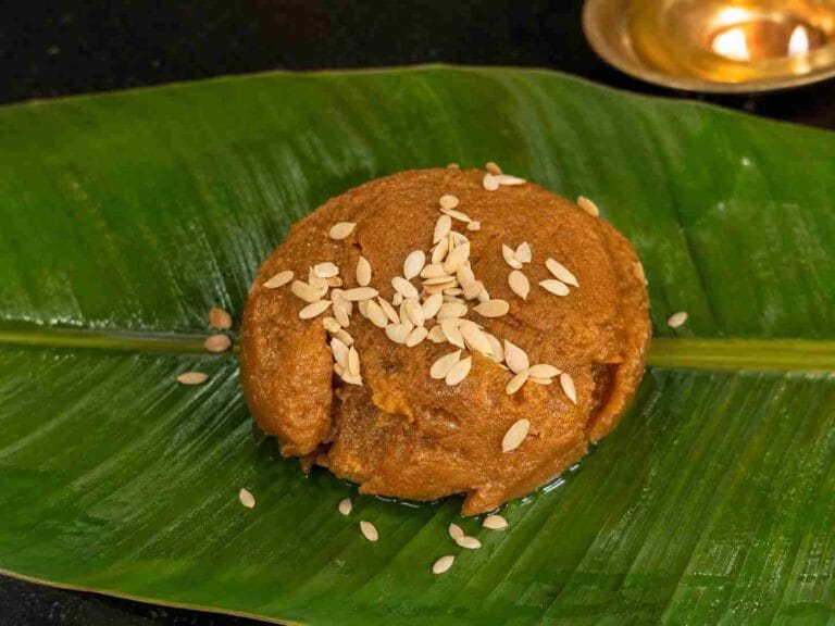 Traditional Aadi Kummayam served on a banana leaf, garnished with pumpkin seeds, showing its smooth texture and rich brown colour.