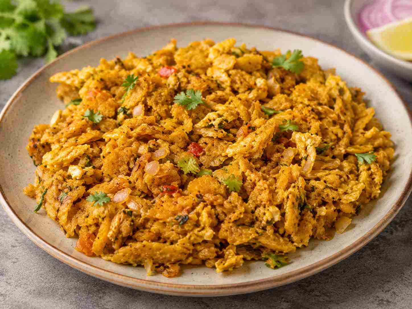 A plate of South Indian egg kothu parotta recipe made with shredded parottas, scrambled eggs, onions, spices, and fresh coriander.