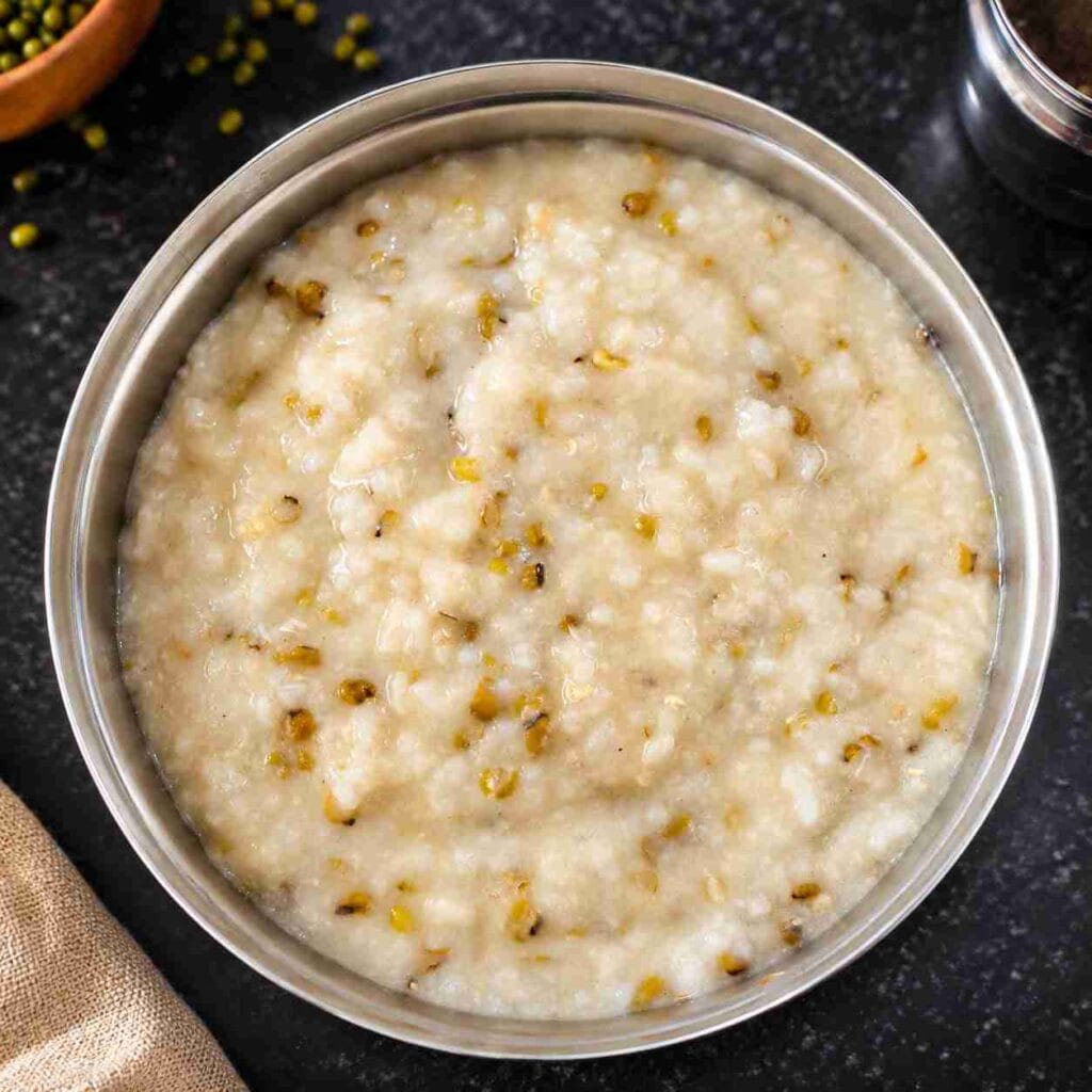 Healthy green gram porridge made with whole green gram, raw rice, garlic, and fresh coconut milk in a steel bowl.