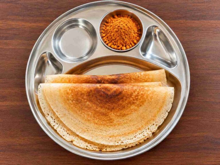 Golden crispy foxtail millet dosas folded and served on a steel plate
