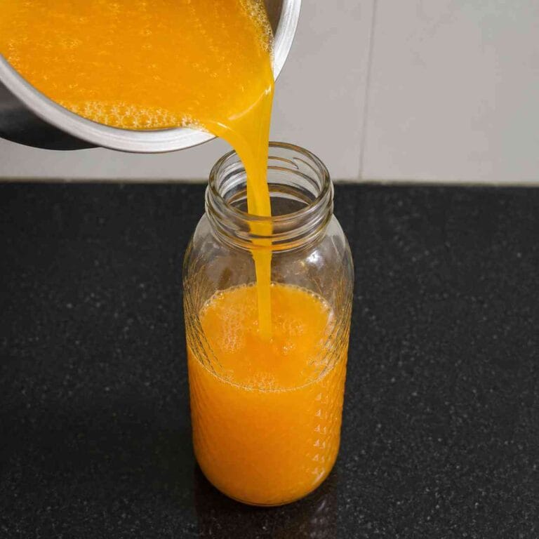 Homemade orange squash being poured into a glass jar