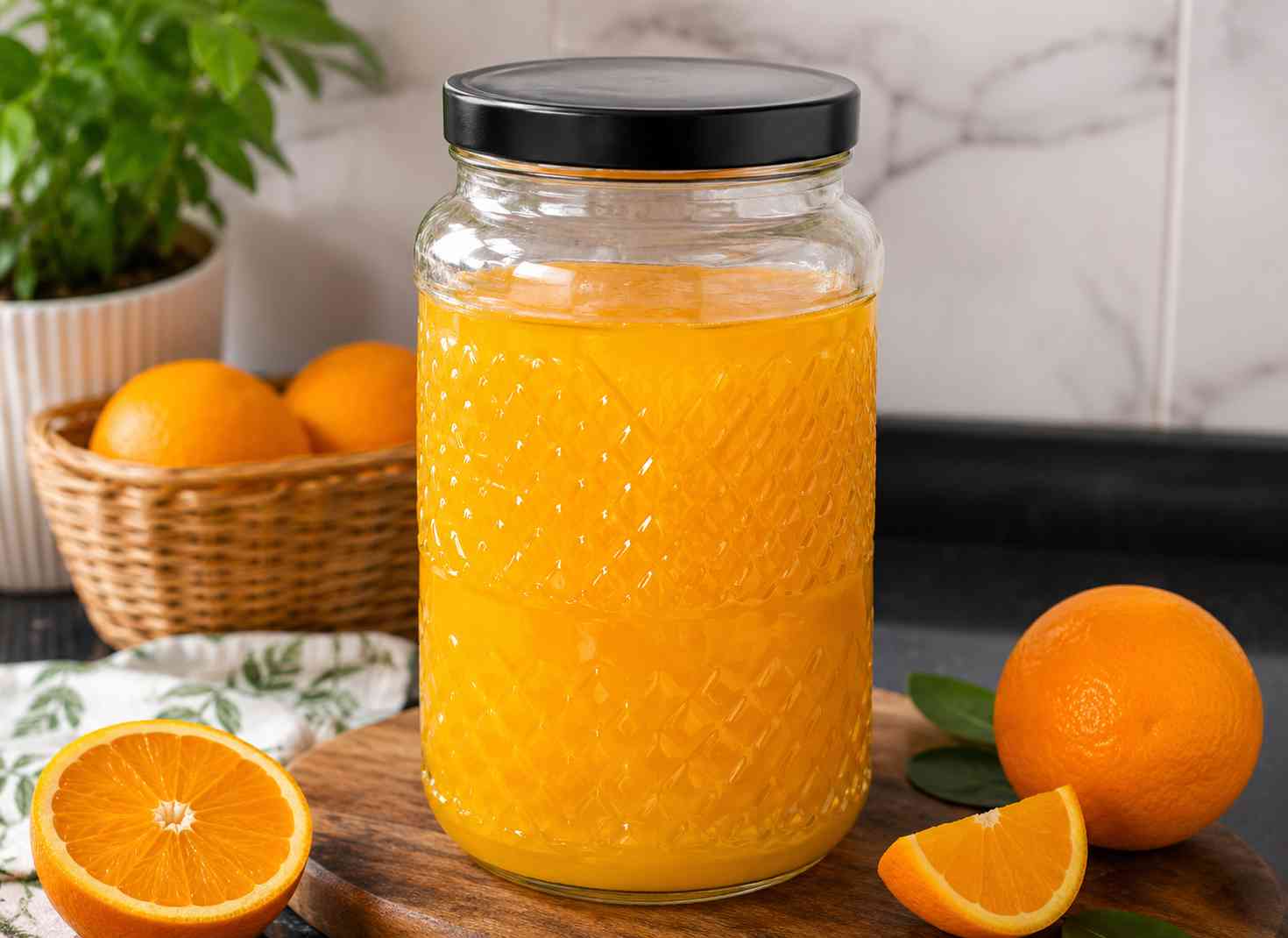 Glass jar filled with bright orange squash beside fresh oranges